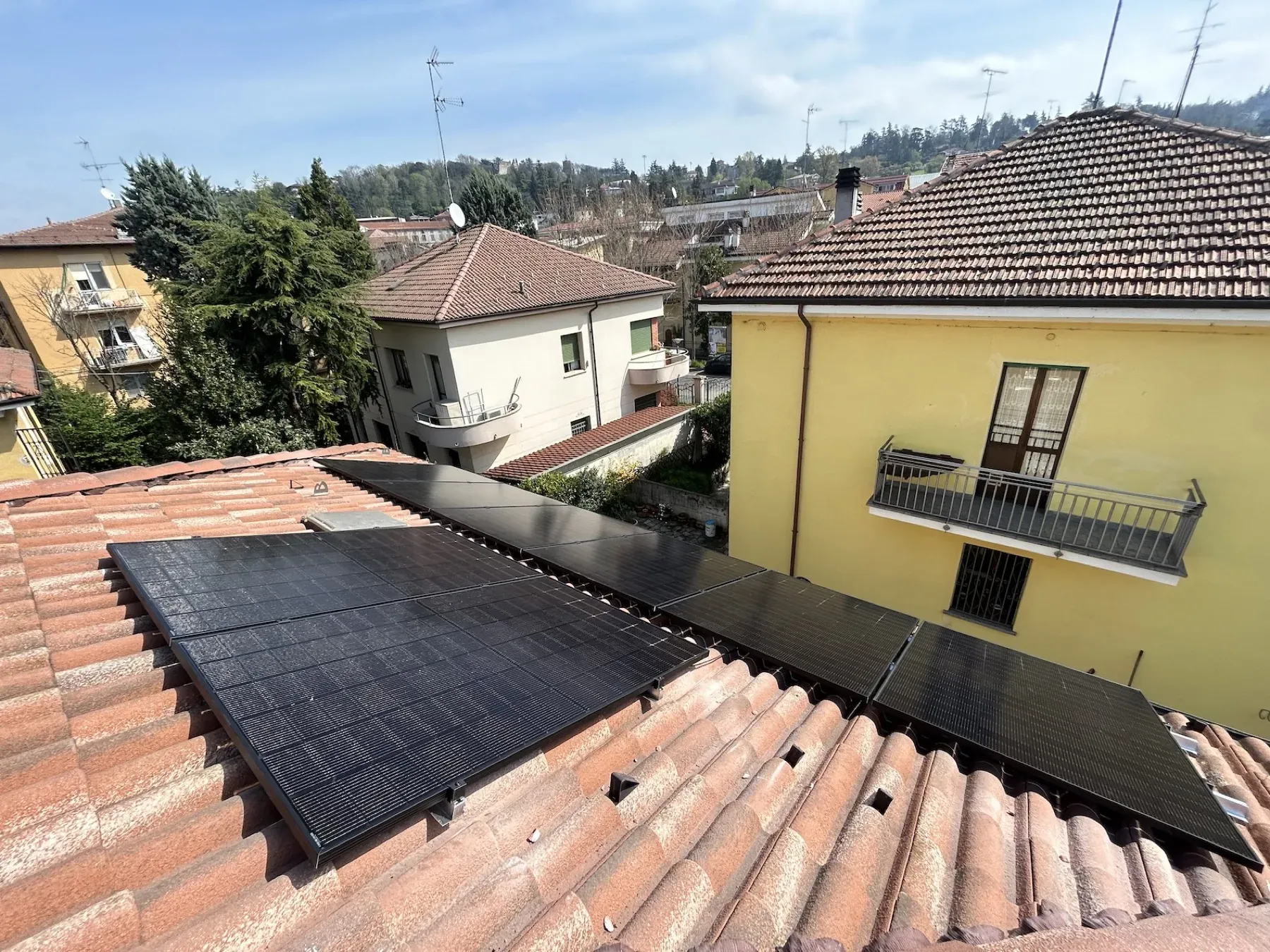 Moduli fotovoltaici su un tetto in coppi, fra case addossate e colorate
