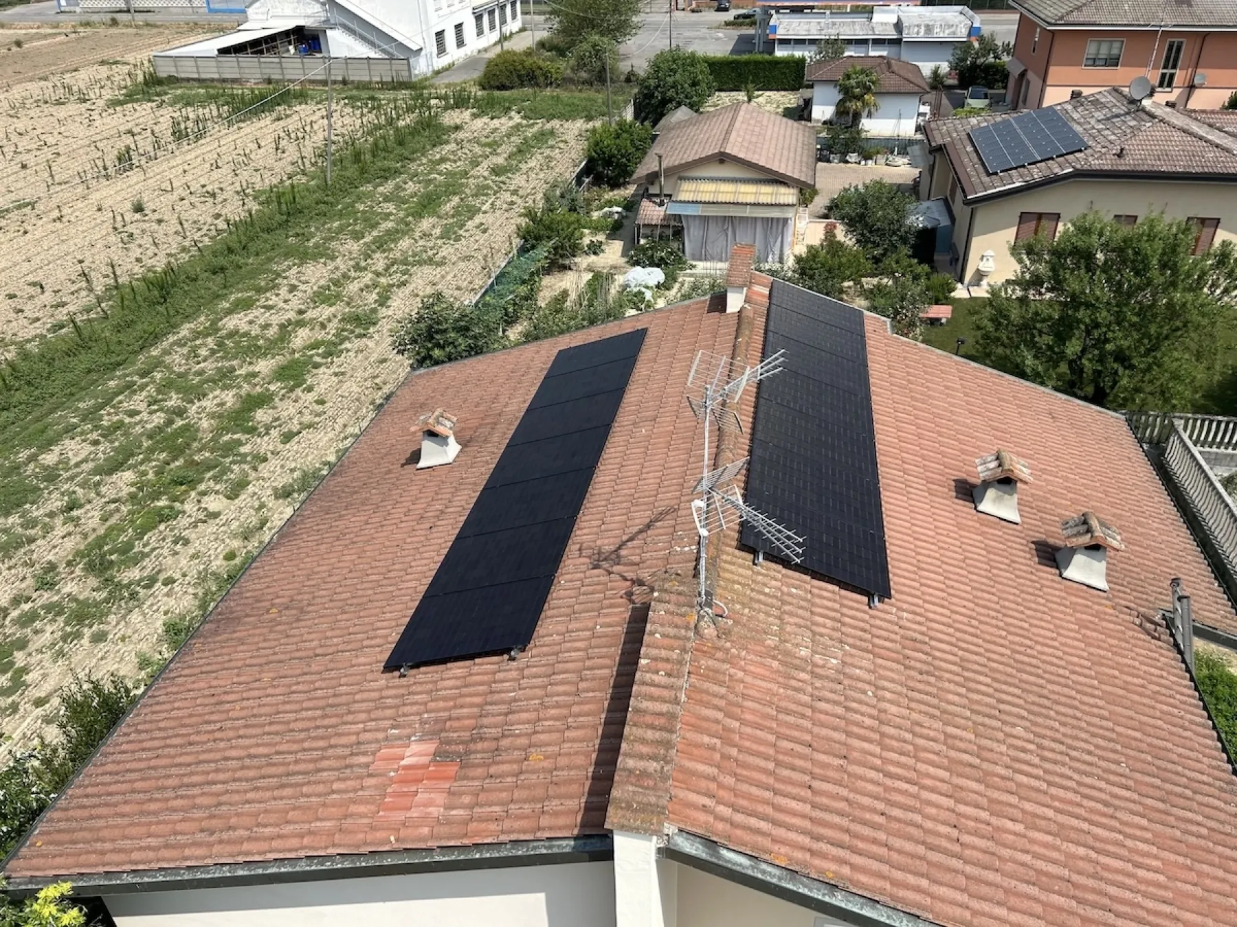 Tetto a falde con moduli fotovoltaici su una casa indipendente, fra i campi della pianura